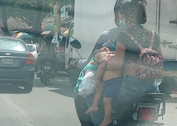 Mujer lleva a bebé en una moto como un paquete